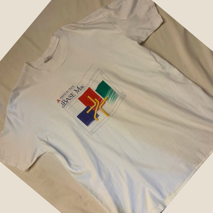 Ashton-Tate dBASE Mac のヴィンテージTシャツ。白地に、緑・赤・青のカラーブロックと黄色い矢印、『ASHTON-TATE dBASE Mac』のロゴがプリントされている。