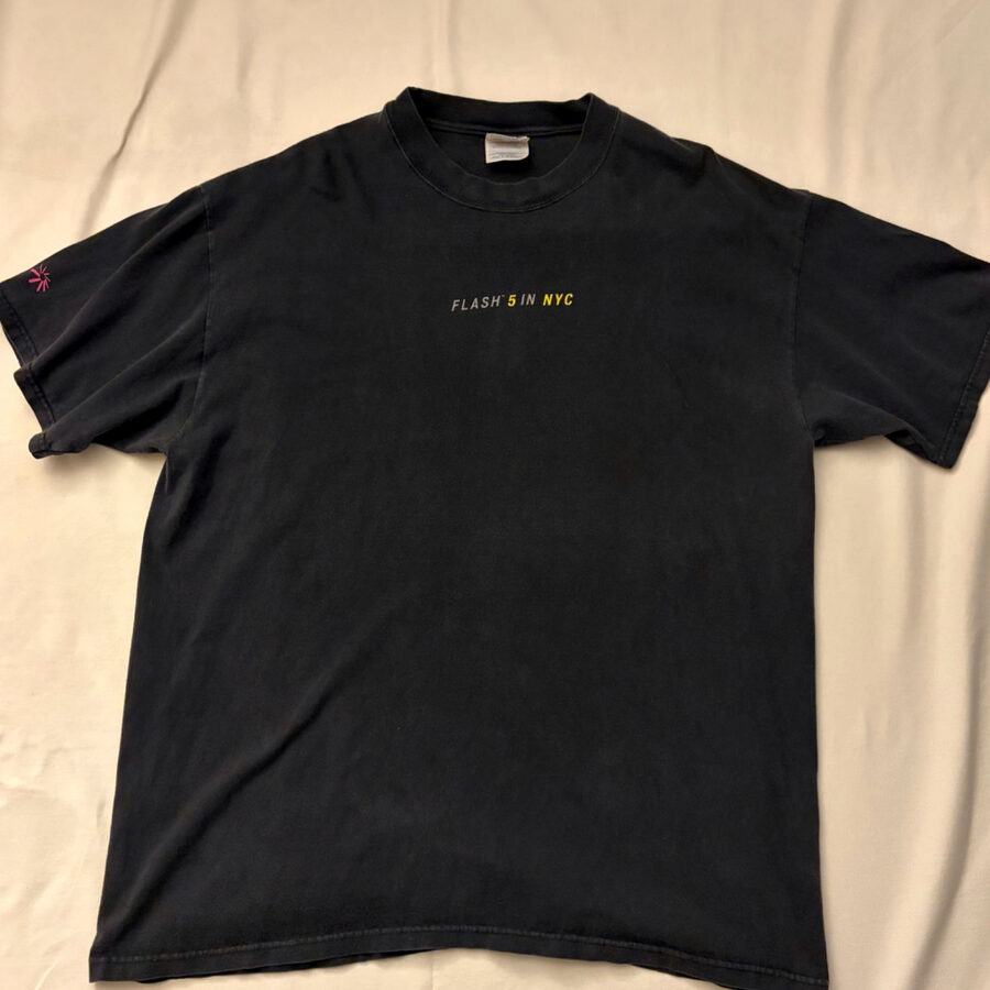 Macromedia Flash 5 のヴィンテージTシャツ。褪色した黒地の胸に『FLASH 5 IN NYC』の小さなプリント、袖にサンバーストのロゴ。