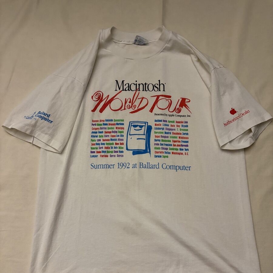 Macintosh World Tour 1992 のヴィンテージTシャツ。白地に『Macintosh World Tour』のロゴ、世界の都市名リスト、『Summer 1992 at Ballard Computer』、両袖に Ballard Computer と Apple Authorized Dealer のプリント。